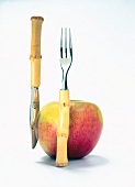 Apple with fruit knife and fork made of bamboo on white background