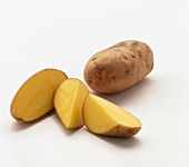 One whole and one sliced agria potato on white background