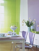 Eßzimmer m dekorativem Hintergrund: die Fliederfarben gestrichene Wand