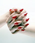 Close-up of woman wearing red nail paint with hands folded
