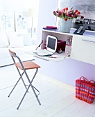 Chair, basket, flower pot and laptop on computer cabinet in room