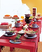 Gedeckter Tisch im asiatischen Stil, Stäbchen, Schalen und Sitzkissen