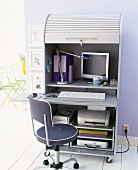 Computer in office cabinet with rolling shutter and sliding shelves with computer space