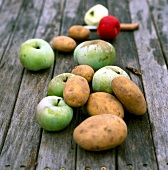 Äpfel und Kartoffeln liegen auf einem Holztisch