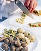 Liver dumplings and potato dumplings on plate and man cutting herb pancake