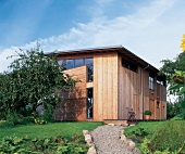 Modernes Holzhaus im Grünen mit Pultdach, Kieselzuwegung