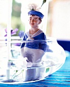Close-up of porcelain man figurine in glass pot with water