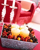 Advent arrangement of four white pillar candles in metal box