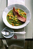 Pea soup with root vegetables, potatoes and pork on plate