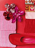 Brooches with sequins, embroidered fabric, red fur shoe and pink scarf on red background