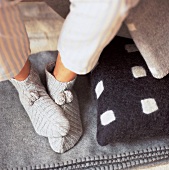 2 Füsse mit Bettsocken aus Baumwolle auf einer Decke aus Wolle