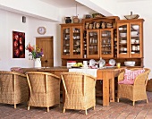 Farmhouse kitchen with buffet on wooden dining table and wicker armchairs