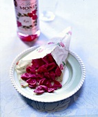 Kandierte Rosenblütenblätter in einer Papiertüte auf einem Teller
