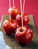Four red apples with skewer on tray