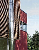 Moderne Fassade; Leistenverkleidung, rote Mauer + Edelstahlschornstein
