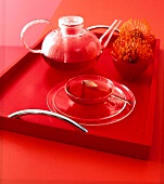 Transparentes Teeservice aus jenaer Glas auf knallrotem Tablett