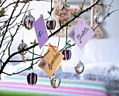 Mini letters and Easter eggs made of glass hanging on branches