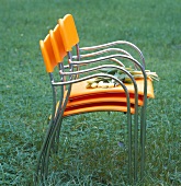 Gestapelte Gartenstühle aus orange- farbenem Kunsstoff und Chrom