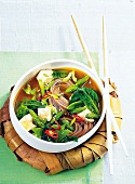 Vegetable soup with buckwheat noodles in bowl with chopsticks