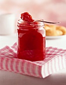 Strawberry and nectarine jam in open jar with spoon