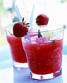 Glass of strawberry daiquiri cocktail with lime and rum garnished with strawberries