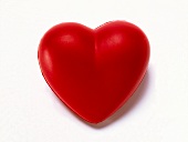 Close-up of red heart made of plastic on white background