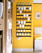 Crockery on hook board made of lacquered metal on yellow wall
