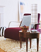 Chair with purple felt cover and oval coffee table with table lamp in front