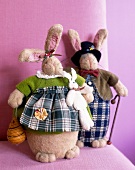 Male and female rabbit dolls in traditional gards on pink background