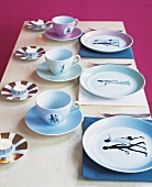Ceramic cups and plates with figures and aroma candles on plates