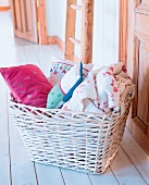 Wäschekorb, weiß, geflochten, mit Rosen-Quilt und verschiedenen Kissen