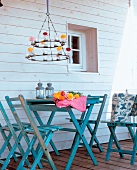 Wrought iron chandelier above blue wooden folding table and chairs