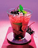 Drink with lime, elderberry, ginger ale and crushed ice in glass