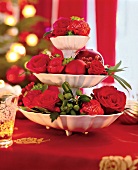 Etagere mit frischen Blüten, roten Rosen, Zweige, Weihnachtskugeln