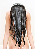 Frau beim Haarewaschen, Haare nach vorne gelegt, Shampoo