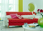 White sofa with red upholstery, pillows and coffee table