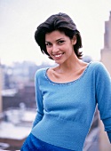 Portrait of pretty woman with dark short hair wearing blue top, smiling