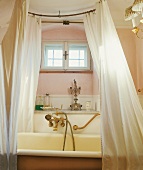 Antike Badewanne, alte Armaturen, weißer Vorhang, rosa Wände