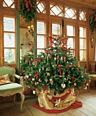 Christmas tree decorated with candles and baubles inside wooden house for Christmas
