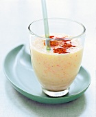 Glass of grapefruit and banana shake with cinnamon powder and straw