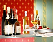 Two glasses of red and white wine in front of several wine bottles