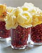 Herbstliche Deko. Freilandrosen stecken in Glas mit Preiselbeeren.