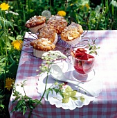 Muffins on metallic grill and rhubarb compote in glass on table surrounded by Woodruff