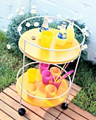 Yellow wooden trolley with bottle of juices and colourful cups