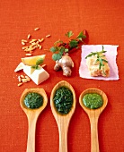 Basil pesto with garlic, olive oil on wooden spoons and parmesan cheese on table