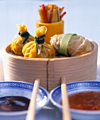 Close-up of tied dumplings, Asian snacks and sauces in bowls with chopsticks