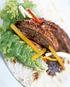 Close-up of duck cantonese and lettuce leaves on tortilla
