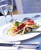 Close-up of marinated lobster with noodle salad on white plate