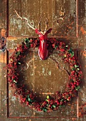 Wreath of rosehips and deer taxidermy hanging on wooden wall