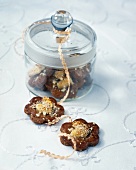Cinnamon and almond dollar cookies in glass jar with lid on white surface